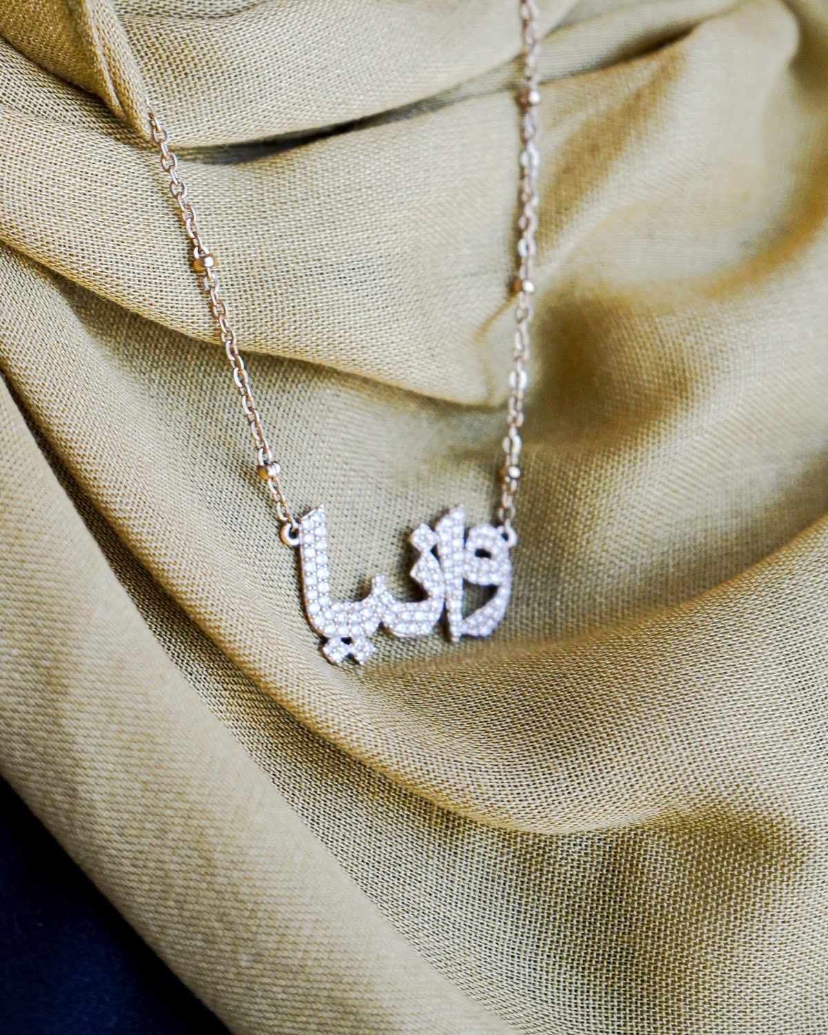 A pavé Arabic name necklace in rose gold
